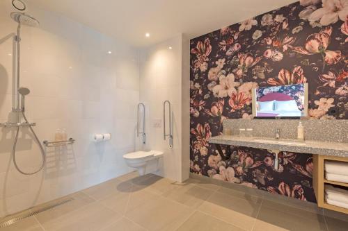 a bathroom with a toilet and a floral wallpaper at Van der Valk Hotel Venlo in Venlo