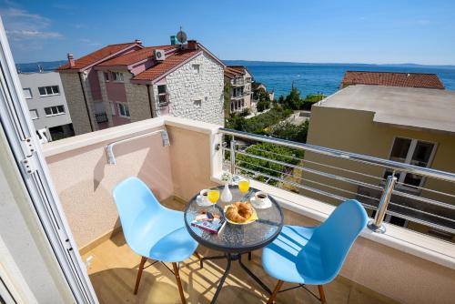 uma varanda com uma mesa e cadeiras e o oceano em San Marian Apartments em Podstrana