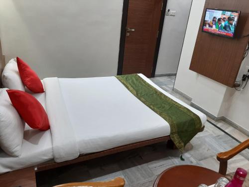 a white couch with red and green pillows in a room at City Palace Hotel होटल सिटी पैलेस in Nashik