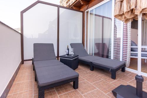 two benches on a balcony with glass walls at Duplex de lujo en la playa , jacuzzy, piscina, chimenea y padel in Benalmádena