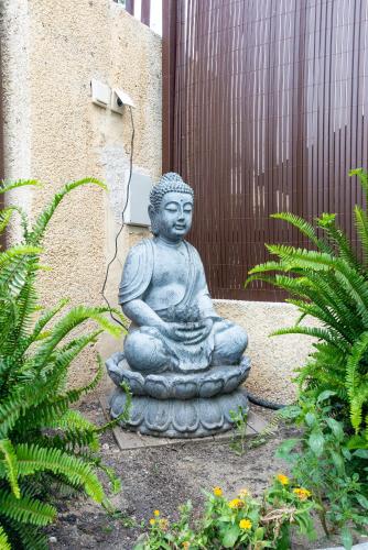 a statue of a buddha sitting in a garden at Duplex de lujo en la playa , jacuzzy, piscina, chimenea y padel in Benalmádena