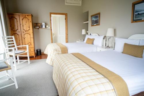 a bedroom with two beds and a chair at Cullinan's Guesthouse in Doolin