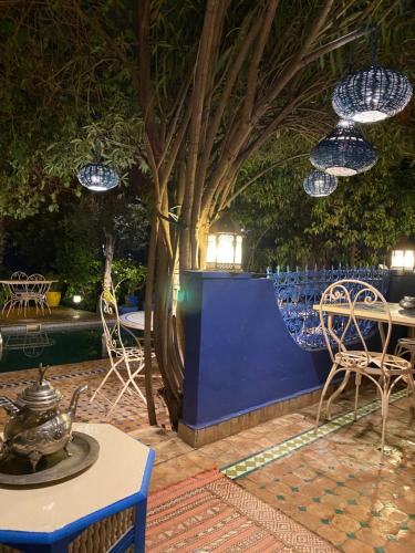 a patio with chairs and tables and blue walls at Riad Jean Claude in Fez
