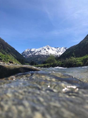 a river with snow capped mountains in the background at Haus Bergwind in Sankt Leonhard im Pitztal
