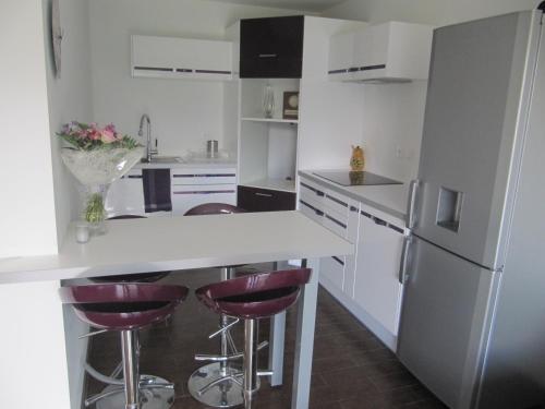 a kitchen with white appliances and purple bar stools at F2 rez de jardin in Ajaccio