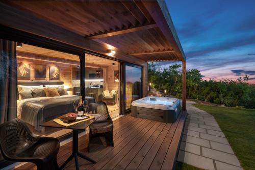 a bedroom and a deck with a bed and a hot tub at Szarvashegy Panoráma Apartman in Szentendre