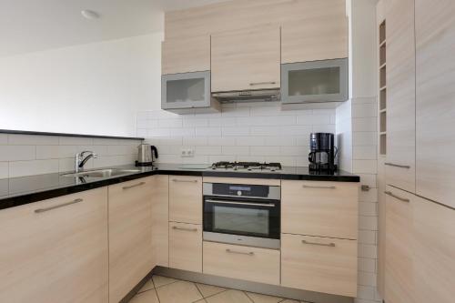 a kitchen with wooden cabinets and a stove top oven at DE TRINTEL met zeezicht in Egmond aan Zee