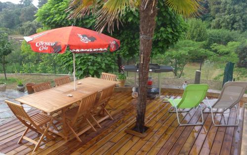 une terrasse en bois avec une table, des chaises et un parasol dans l'établissement F2 rez de jardin, à Ajaccio