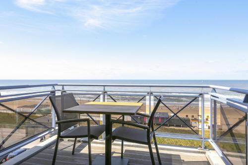 a table and chairs on a balcony with the beach at DE TRINTEL met zeezicht in Egmond aan Zee