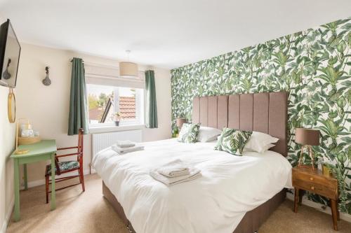 a bedroom with a large white bed with a green and white wallpaper at The Fromeway in Radstock