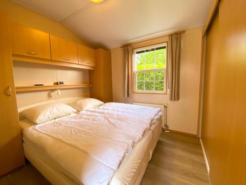 Cette chambre comprend un grand lit et une fenêtre. dans l'établissement Hello Zeeland - Vakantiehuis Paarlhof 51, à Groede