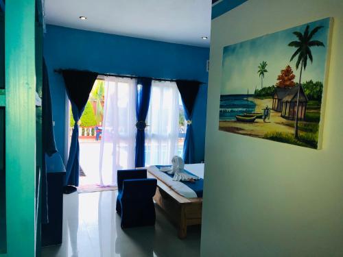 a room with blue walls and a painting on the wall at Petite Flower Guest House in Talata-maty