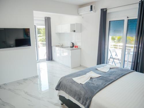 a white bedroom with a bed and a kitchen at Apartments Gjenashaj in Ulcinj