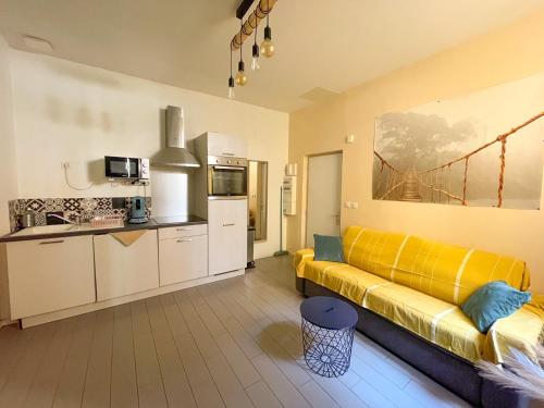 a living room with a yellow couch and a kitchen at New! Cosy T2 au coeur de la ville - climatisation - coin terrasse in Aix-en-Provence