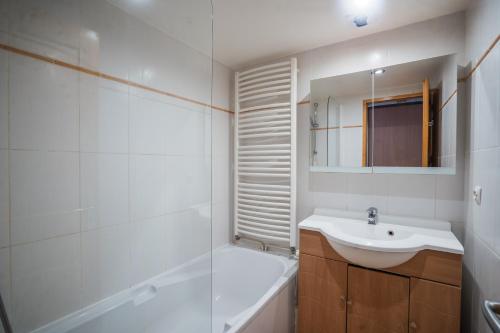 een badkamer met een wastafel, een bad en een spiegel bij 130m2 ,5 chambres, trés bien situé in Les Deux Alpes