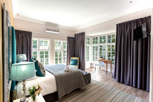 a bedroom with a bed and some windows at Taunton Manor in Pietermaritzburg