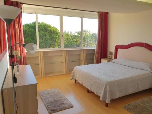 a bedroom with a bed and a large window at Parque das Amendoeiras in Vilamoura