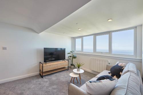 two people sitting on a couch in a living room with a tv at Host & Stay - Pier View Penthouse in Whitby