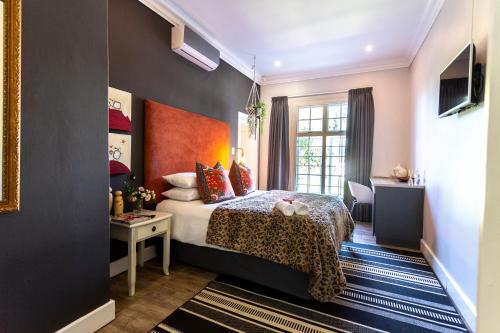 a hotel room with a bed and a desk at Taunton Manor in Pietermaritzburg