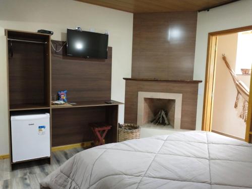 a bedroom with a bed and a fireplace at Chalés do Pardal in Visconde De Maua