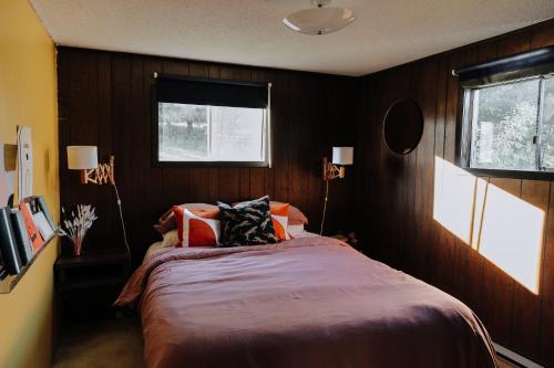 a bedroom with a bed with wooden walls and two windows at Colonial Bay Motel and Cottages in Huntsville