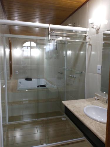 a glass shower in a bathroom with a sink at Chalés do Pardal in Visconde De Maua