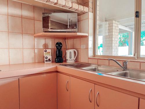 una cucina con armadi arancioni, lavandino e finestra di Carnarvon 3BR & 2BA Holiday House a Carnarvon