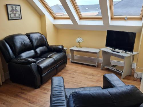 a living room with a black leather couch and a desk at Arasáin Bhalor in Falcarragh