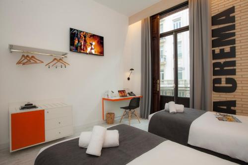 a hotel room with two beds and a desk at Casual Socarrat Valencia - Adults Only in Valencia