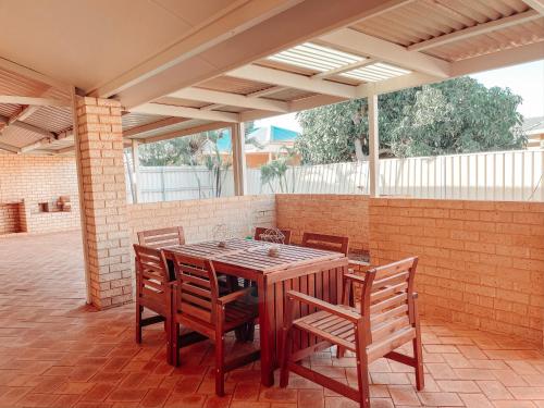 einen Holztisch und Stühle auf einer Terrasse in der Unterkunft Carnarvon 3BR & 2BA Holiday House in Carnarvon