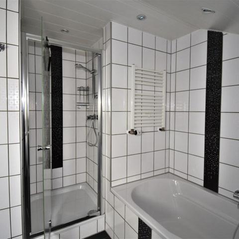 a white tiled bathroom with a tub and a shower at FeWo 4 - Erpolzheim in Erpolzheim