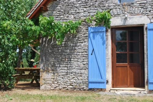 an old stone building with a blue door and a table at Le Chant du Coq in Lacave