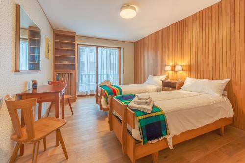 una camera da letto con due letti, un tavolo e una scrivania di APPARTAMENTO CAMILLE - Accogliente appartamento - COUR 0078 a Courmayeur