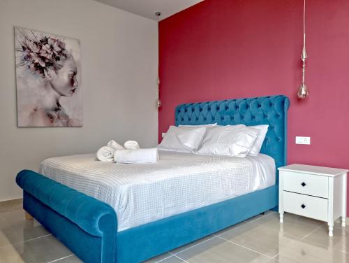 a bedroom with a blue bed and a pink wall at Epipleon Luxury Suites - 107 - Διαμέρισμα 85τμ - Θέα στη θάλασσα in Nafpaktos