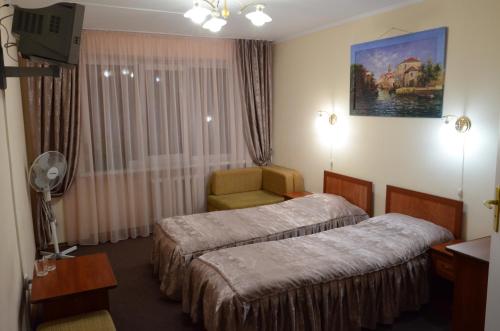 una habitación de hotel con 2 camas y una silla en Burger Plus Inn en Leópolis