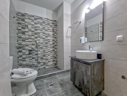La salle de bains est pourvue de toilettes, d'un lavabo et d'un miroir. dans l'établissement Epipleon Luxury Suites - 107 - Διαμέρισμα 85τμ - Θέα στη θάλασσα, à Naupacte