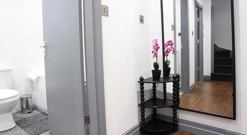 un baño con espejo y una mesa con flores. en Central Northern Quarter Apartment Sleeps Upto 4, en Mánchester