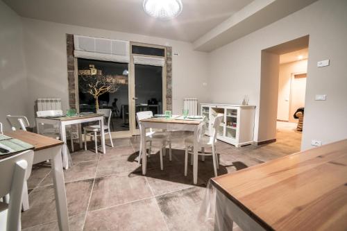 Un comedor con mesas blancas y sillas blancas. en La Casa Tra Gli Ulivi, en Asís