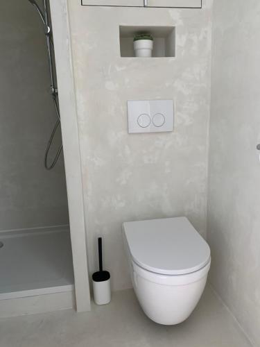 a white bathroom with a toilet and a shower at Strandcabane in Nieuwpoort