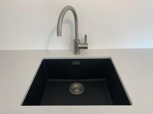 a black kitchen sink with a chrome faucet at Strandcabane in Nieuwpoort