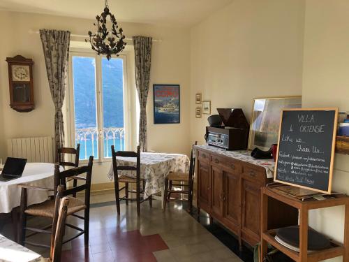 a dining room with a table and chairs and a window at B&B Villa le Ortensie in Faggeto Lario 