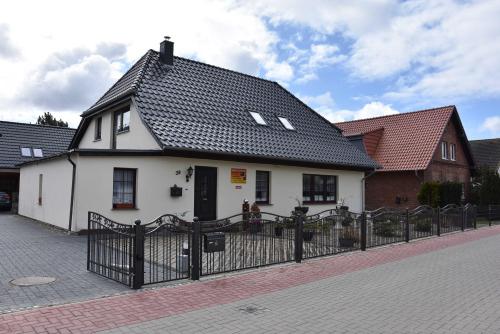 ein weißes Haus mit schwarzem Dach hinter einem Zaun in der Unterkunft Karlshagen - Lissis Feriendomizil in Ostseebad Karlshagen