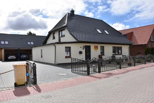 ein weißes Gebäude mit einem schwarzen Dach auf einer Straße in der Unterkunft Karlshagen - Lissis Feriendomizil in Ostseebad Karlshagen