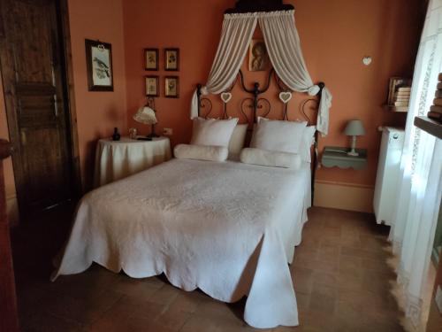 1 dormitorio con 1 cama blanca con dosel en B&B Il Salice, en Veruno