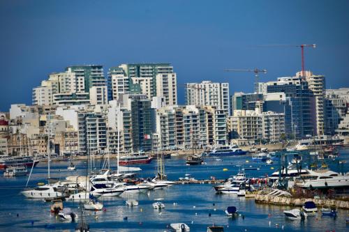 a group of boats docked in a harbor with a city at Shore Bridge in Il-Gżira