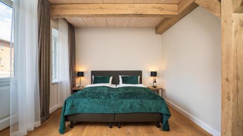 Schlafzimmer mit einem Bett mit grüner Tagesdecke in der Unterkunft Antik-Hof Bissee in Bissee