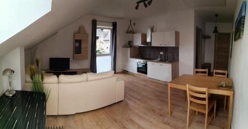 ein Wohnzimmer mit einem weißen Sofa und einem Tisch in der Unterkunft Sonnenufer Apartment & Moselwein I in Bernkastel-Kues