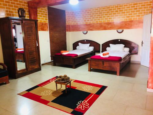 a room with two beds and a table in it at Petite Flower Guest House in Talata-maty