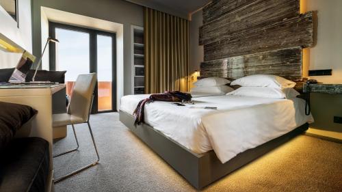 a bedroom with a large white bed and a desk at Vitoria Stone Hotel in Évora