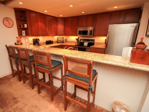 a kitchen with a counter with chairs and a refrigerator at Mountainback #111 in Mammoth Lakes